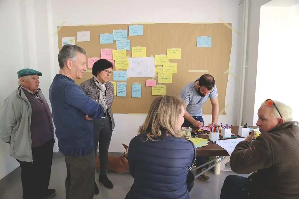 Un atelier participatif : des participants de tous âges devant un mur couvert de post-it.